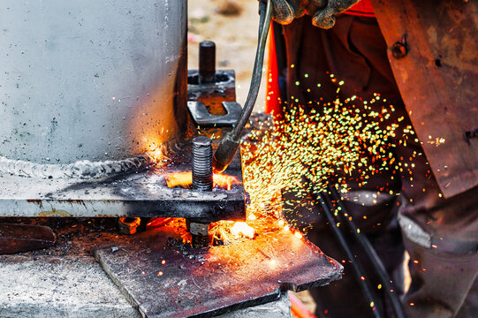 Worker cutting metal plate by Gas Cutting Torch at a construction site. Installation of a metal structure. Close-up. The welder performs the installation of metal structures. Sparks from welding.