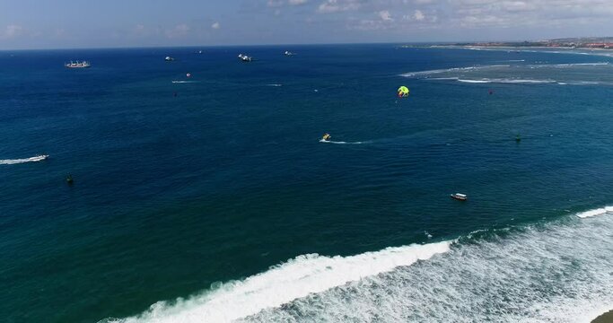 Aerial shot of parasailing boats going over blue water