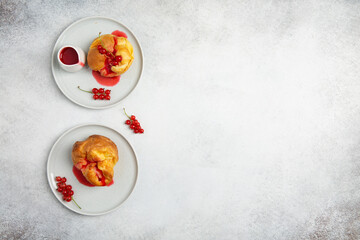 Homemade yorkshire pudding with redcurrant sauce on gray plates on concrete background. Top view.  Copy space.