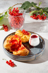 Homemade yorkshire pudding with redcurrant sauce on gray plates on concrete background.