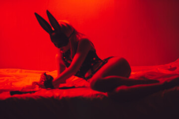 blurry silhouette of sexy submissive girl in underwear and a mask lies on bed in bedroom. BDSM...
