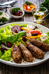 Souvlaki - greek shashlik served with fresh green vegetables and feta cheese on wooden table
