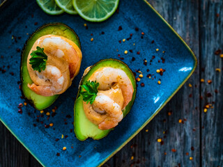 Avocado with fried prawns on and cocktail sauce on wooden background

