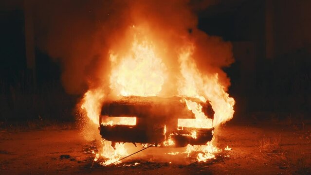 Abandoned car engulfed in flame after shelling, located at residential area at night
