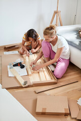 Mother and daughter assembling new furniture - moving in into a new home.