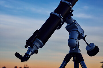 Big astronomical telescope under a twilight sky ready for stargazing.