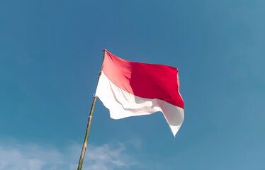 Indonesian flag with a bamboo pole flying high in the sky. Indonesian independence day August 17th