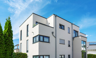 Fototapeta na wymiar Weißes modernes kubistisches Wohnhaus mit Apartment mit Balkon in einem Wohngebiet in Deutschland