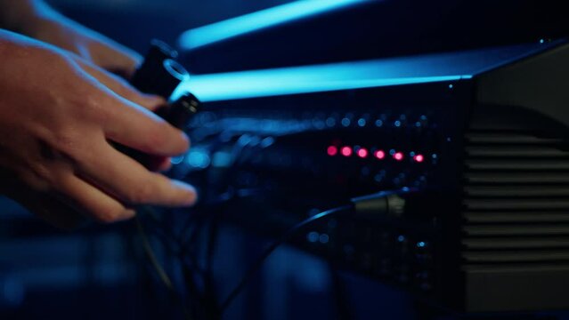 Close-up of a man plugging an XLR cable into a professional speaker. Setting up the equipment before the concert