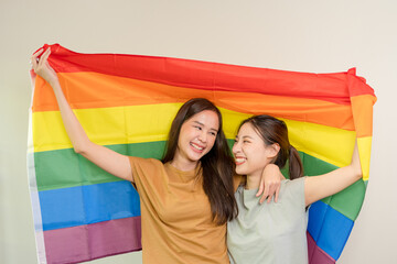 LGBT group. Good looking lesbian couples smile brightly cover rainbow flags. Asian couple hugging each other happily, lover in love