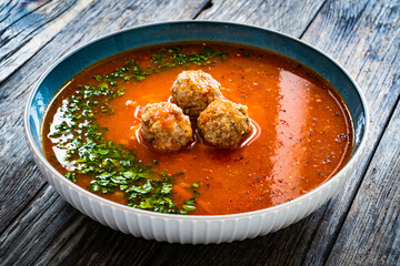 Tomato soup with pork meatballs and fresh parsley on wooden table
