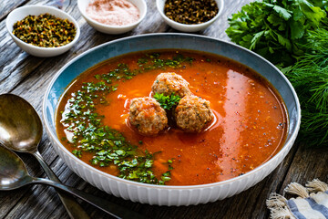 Tomato soup with pork meatballs and fresh parsley on wooden table
