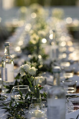 Decorated elegant edding table in rustic style with eucalyptus and flowers, porcelain plates and glasses. Vertical