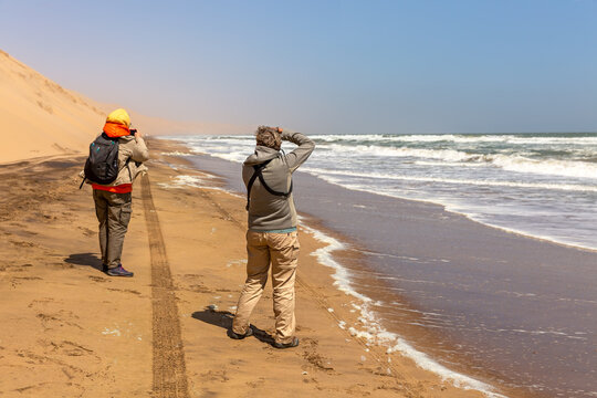 Tourists take pictures of the dunes and the ocean at Sandwich Harbor. Namibia