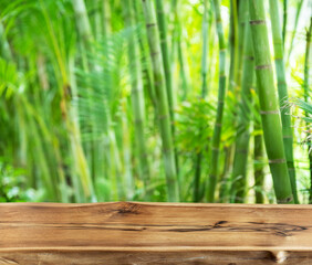 Empty wooden board or table top and blurred green bamboo culms. Place for your product display.