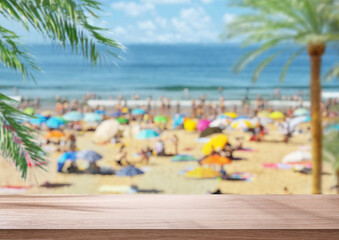 Empty table top and blurred photo of crowded ocean beach  in the summer day. Vacation background.
