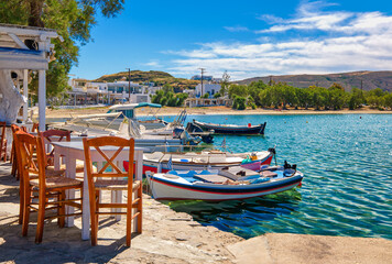 Fototapeta na wymiar Colorful chairs and tables of Greek tavern by waterfront at day. Vacations, Greece, summer, restaurant, outdoor dining, islands, port, marina, yachts