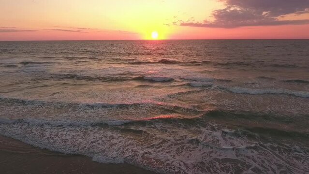 Cinematic drone shot of the ocean with the sun setting or rising on the Atlantic ocean