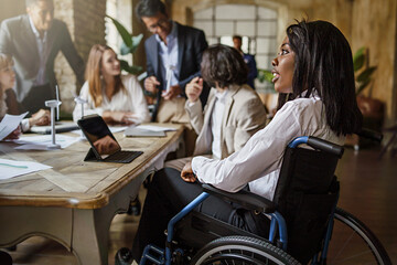 Office coworkers in the meeting room - main focus on African American woman with disabilities...