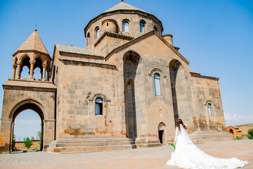 Fototapeta premium Bride in a white dress at the church. Wedding photo at the church. Bride and Church. Wedding bouquet in the hands of the bride