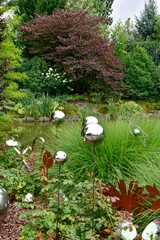 A show garden with grasses, a lake and various decorations in Poland.