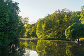 Lake in the city park in sunset, nature landscape with sunlight