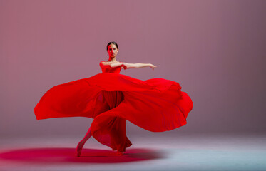 A young graceful ballerina, dressed in pointe shoes and a weightless red skirt, demonstrates her dancing skills. The beauty of classical ballet.