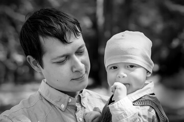 Life style portrait of a family in the park, father holding his little son in his arms, family happiness, black and white photography