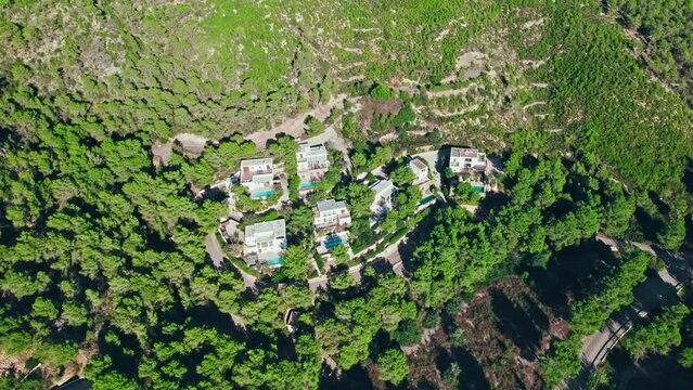 Luxury residences, mansions and pool suites by Cala Es Canaret on Ibiza. Aerial drone view of the north coast of Ibiza, Balearic Islands, Spain with beautiful green forest and rocky caves.