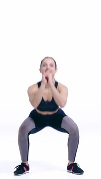 vertical video of happy sportswoman doing squat exercise on white