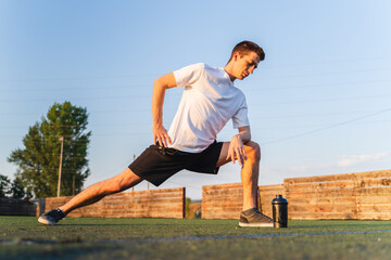 A young guy stretching, warming up and doing push up outside in nature during the day