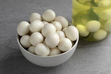 Bowl with preserved cooked Quail eggs close up and a glass jar on the background