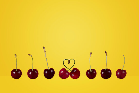 single couple concept row of ripe cherries pair heart cherries fruit on a colorful colourful yellow background