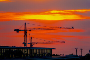 construction cranes against the backdrop of the setting sun