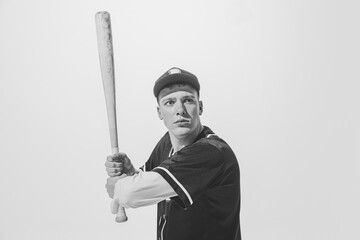 Black and white portrait of concentrated young man, baseball player in uniform with bat preparing...