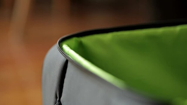 A stationary closeup footage of a gray suitcase being unzipped and opened single handedly..