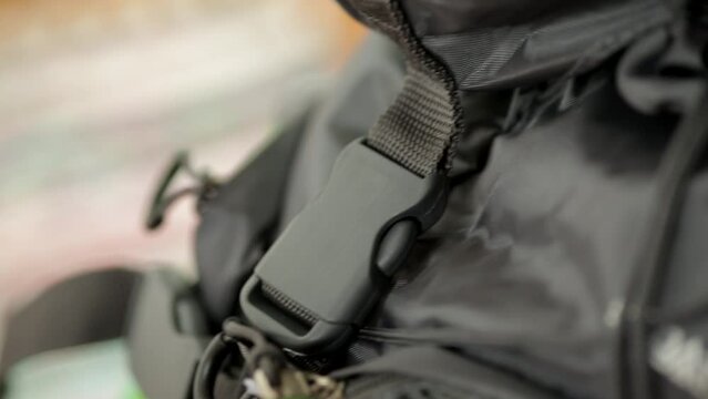 A handheld footage of a backpack where its buckle is being closed by the hands of the traveller..