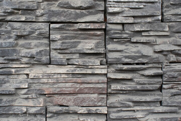 Texture of tiles and flat gray stones stacked on top of each other. Art trim on the wall of the house.