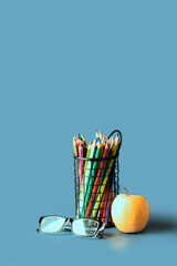 Fototapeta Back to school and studying concept. Colourful pencils, glasses and apple fruit on blue background.Copy space. obraz