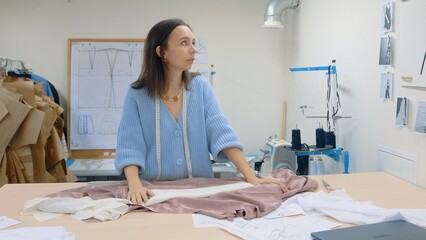 Obraz premium 4K. The seamstress creates an individual dress in the workshop. The girl prepares the fabric for work