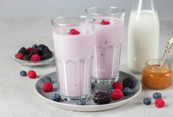 Fototapeta Smoothie from berries, natural yogurt and honey in two tall glasses on gray background obraz