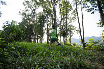 Woman trail runner running at tropical forest mountain peak