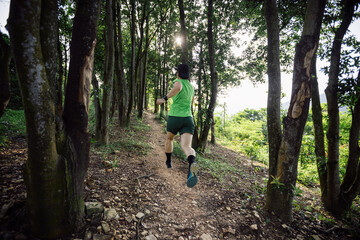 Fototapeta Woman trail runner running at tropical forest mountain peak obraz