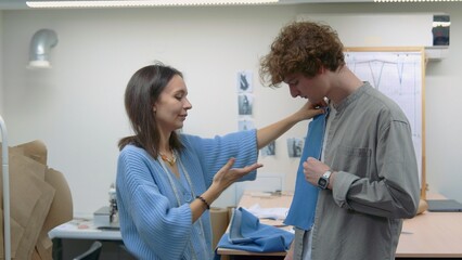 Obraz premium 4K. A young seamstress works with a client in a sewing workshop. They pick up the fabric