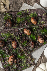 Halloween concept food. Flatbread or pizza with squid Ink, green cheese, mushrooms and purple onion