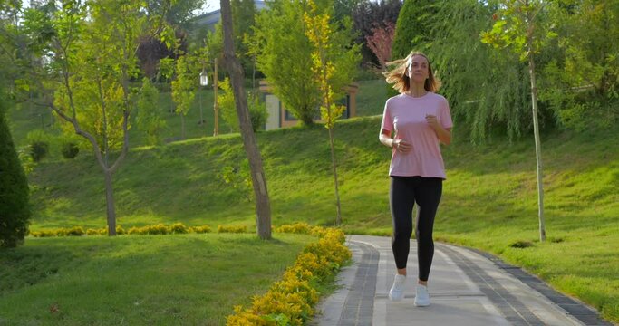 Young woman working out in the park, holding her injured knee in slow motion.