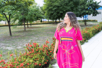 Latina woman walking in traditional clothing in a city park.