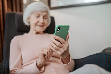 Elderly lady in beige blouse with a smartphone in hand