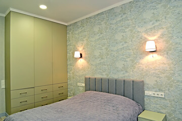 Double bed and wardrobe in the bedroom with wall lamps