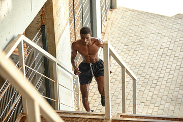 Sport Motivation. Black Male Athlete Running Up On Urban Stairs Outdoors, Enjoying Morning Workout, With Free Space